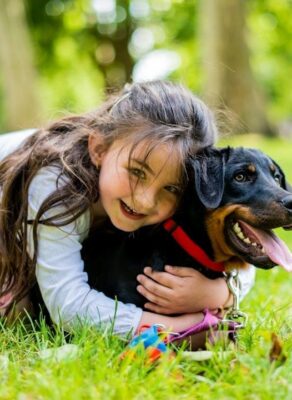Kind omhelst een aangelijnde hond in het gras