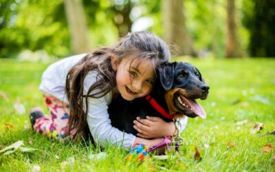 Kind omhelst een aangelijnde hond in het gras