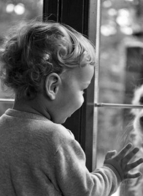 Kind kijkt door het raam naar een hond buiten