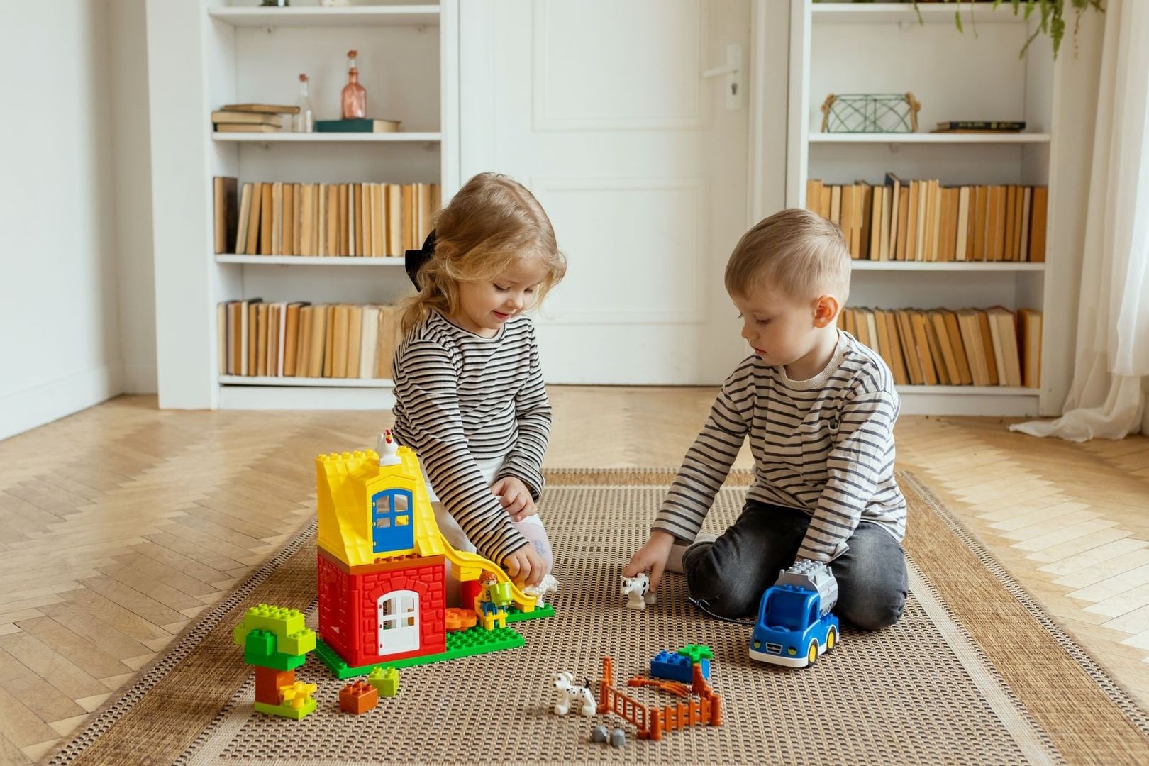 Twee jonge kinderen spelen samen met bouwblokken op een kleed